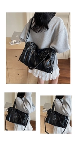Dettaglio borsa tote in pelle nera lucida con cerniere in metallo e tracolla regolabile