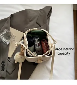 Draufsicht auf das geräumige Innere einer beigen Beuteltasche mit Zubehör und Plüsch