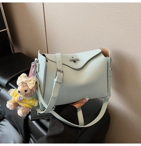 Close-up of light blue pebble leather bag with silver buckle and cute teddy bear charm