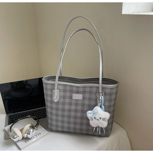 Detail of gray checkerboard tote bag with silver handles and fluffy cloud charm accessory