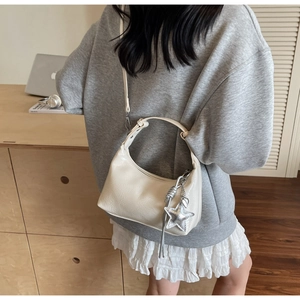 Détail du sac demi-lune crème avec texture en cuir plissé et pendentif étoile