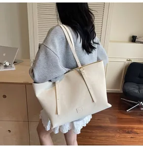 Détail du sac fourre-tout en cuir blanc crème avec logo HAMIROO embossé sur le côté