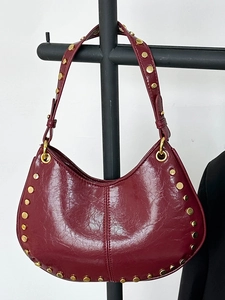Retro burgundy hobo bag with gold studs and polished finish in a modern bucket style