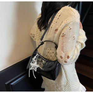 Détail du sac demi-lune en cuir verni noir brillant avec breloque étoile argentée