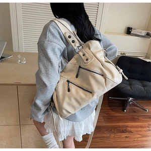 Dettaglio della borsa da viaggio in pelle bianco crema con zip in metallo e tracolla