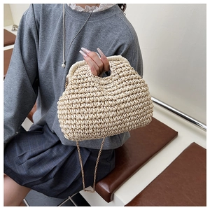 Détail d'un sac en paille beige avec chaîne métallique fine et texture tissée dense