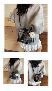 Detail of grey plaid bucket bag featuring a white plush sheep pendant and golden hardware
