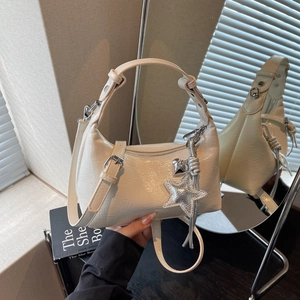 Détail du sac à bandoulière blanc crème brillant avec ses breloques étoile et cœur