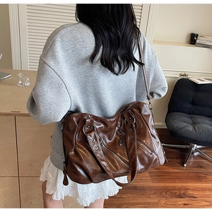 Dettaglio della grande borsa da viaggio vintage in pelle PU marrone con borchie e cerniere