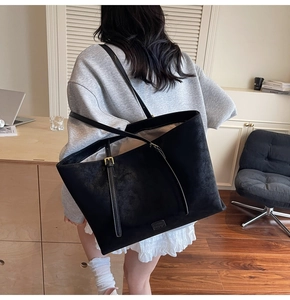 Détail du grand sac cabas noir avec boucle dorée sur la bandoulière et finition mate