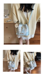 Detail of light blue plaid bucket bag with plush sheep charm and leather trim details
