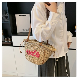 Détail du sac cabas en paille tissé à la main avec broderie Hello rose et cuir
