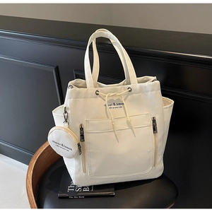 Detail view of the cream canvas tote bag showing the drawstring closure and small round pouch