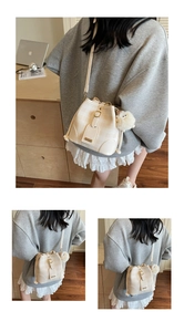 Detail of creamy white bucket bag with drawstring closure and plush pendant in home setting