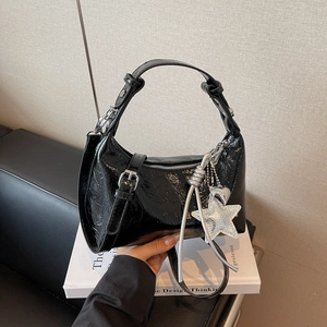 Détail du sac hobo en cuir verni plissé noir avec breloque étoile argentée et boucle métal