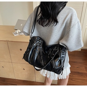 Dettaglio della texture in pelle PU nera pieghettata e rivetti argentati sulla borsa