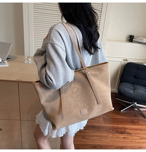 Vue détaillée du grand sac cabas en daim kaki avec logo de marque embossé au fond