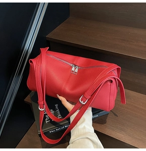 Detail of red lychee pattern leather shoulder bag featuring dual zipper closure