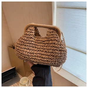 Détail d'un sac à main en paille tressée avec chaîne dorée et poignée intégrée sur table