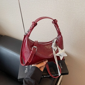 Détail du sac hobo en cuir verni rouge foncé avec breloques étoile et cœur en argent