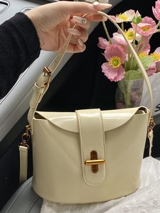 Elegante cremefarbene Lackleder-Beuteltasche mit Goldschließe in luxuriöser Umgebung