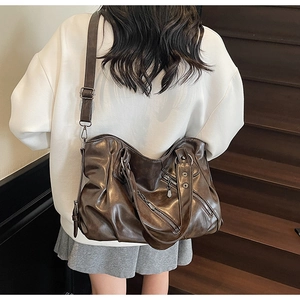 Dettaglio posteriore di una borsa da viaggio vintage in pelle morbida marrone su modella