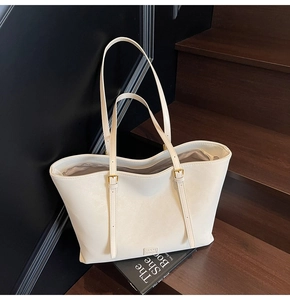 Détail d'un sac cabas blanc avec des bretelles réglables et des ferrures dorées