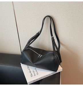 Close-up of black lychee grain leather tube bag with silver hardware and dual zippers