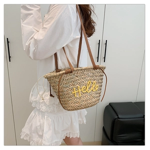 Détail du sac cabas en paille tressée avec broderie Hello jaune et anses en cuir élégant