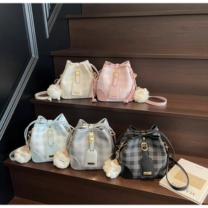 Detailed view of bucket bags in five colors with drawstring and plush pom-poms