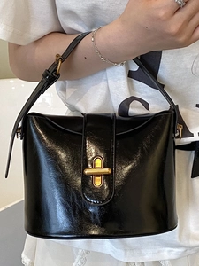 Glänzende schwarze Beuteltasche mit goldenem Kreuzverschluss und Schultergurt