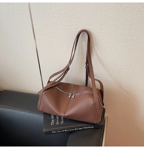 Close-up of brown litchi pattern leather shoulder bag with dual zipper and adjustable straps