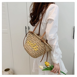 Détail du sac cabas en paille tissé avec anses en cuir et broderie Hello jaune