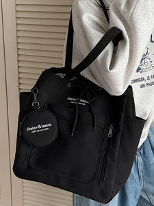 Minimalist black canvas tote bag with a small round pouch and large storage capacity