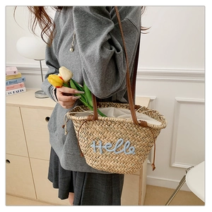 Détail du sac cabas en paille avec broderie Hello bleue et anses en cuir marron