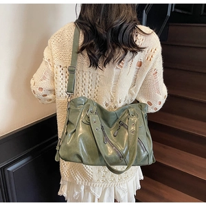 Dettaglio borsa da viaggio vintage verde con tasche a zip e occhielli in metallo