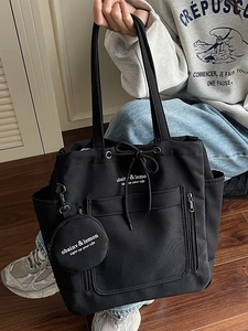 Minimalist black large capacity canvas tote bag with hanging coin purse shown on model