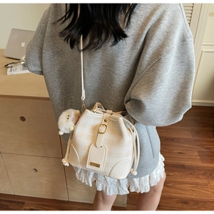 Detail of cream checkerboard bucket bag with drawstring closure and cute sheep pendant