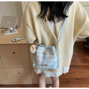 Detail of light blue checkered bucket bag with leather strap and cute lamb pendant