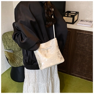 Detail of white bucket bag with elegant butterfly pattern and pearl bow charm accessory
