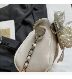 Close-up of luxury white soft leather bag with silver chain and pearl ornaments