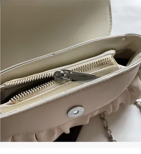 Detail of the smooth metal zipper and magnetic closure on a soft cream cloud bag