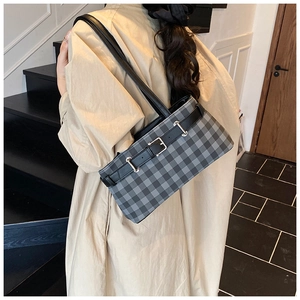 Classic grey plaid shoulder bag with silver buckle worn by a model in a minimal setting