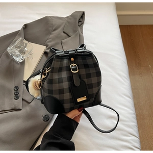 Detail of checkered bucket bag with gold buckle, plush charm, and black leather trim