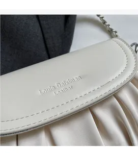 Detail shot of beige cloud bag featuring luxury pleated leather texture and silver chain strap