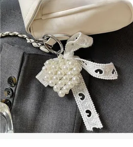 Detailed macro of heart-shaped pearl charm with lace bow on white soft leather bag