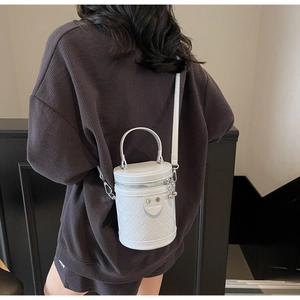 Nahaufnahme einer weißen gesteppten Zylindertasche mit Lederriemen getragen von einem Modell