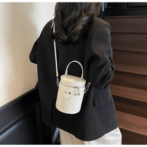 Gesteppte weiße Beuteltasche mit schwarzem Blazer am Modell an der Treppe