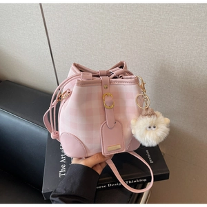 Detail of pink plaid bucket bag with a plush lamb charm and gold metal buckle