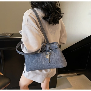 Close-up of the grey-blue denim shoulder bag with silver metal lock and key charm detail